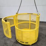 Crane hoisting material basket. Side view, open door
